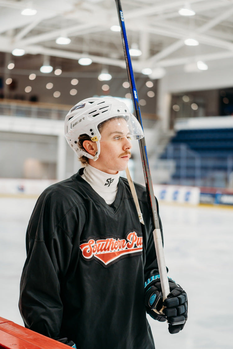 Hockey player on the ice wearing the white Southern Puck neck guard collar beneath a jersey